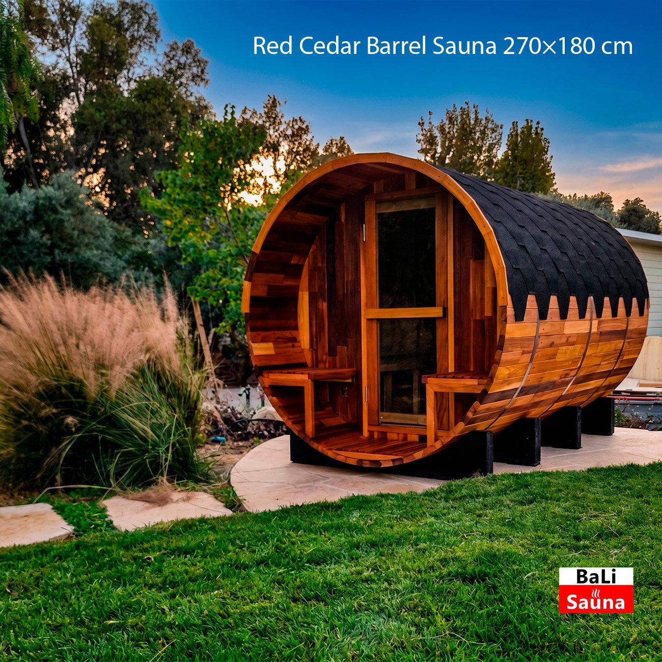 Red cedar barrel sauna (270×180 cm) on a patio with green lawn and sunset sky; BaLi Sauna logo bottom right.