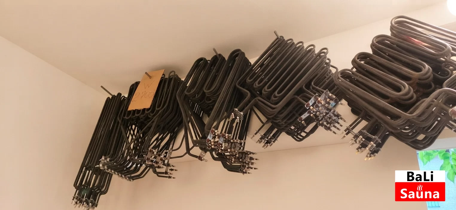 Row of curved black sauna heater coils hanging from a showroom ceiling with price tags attached